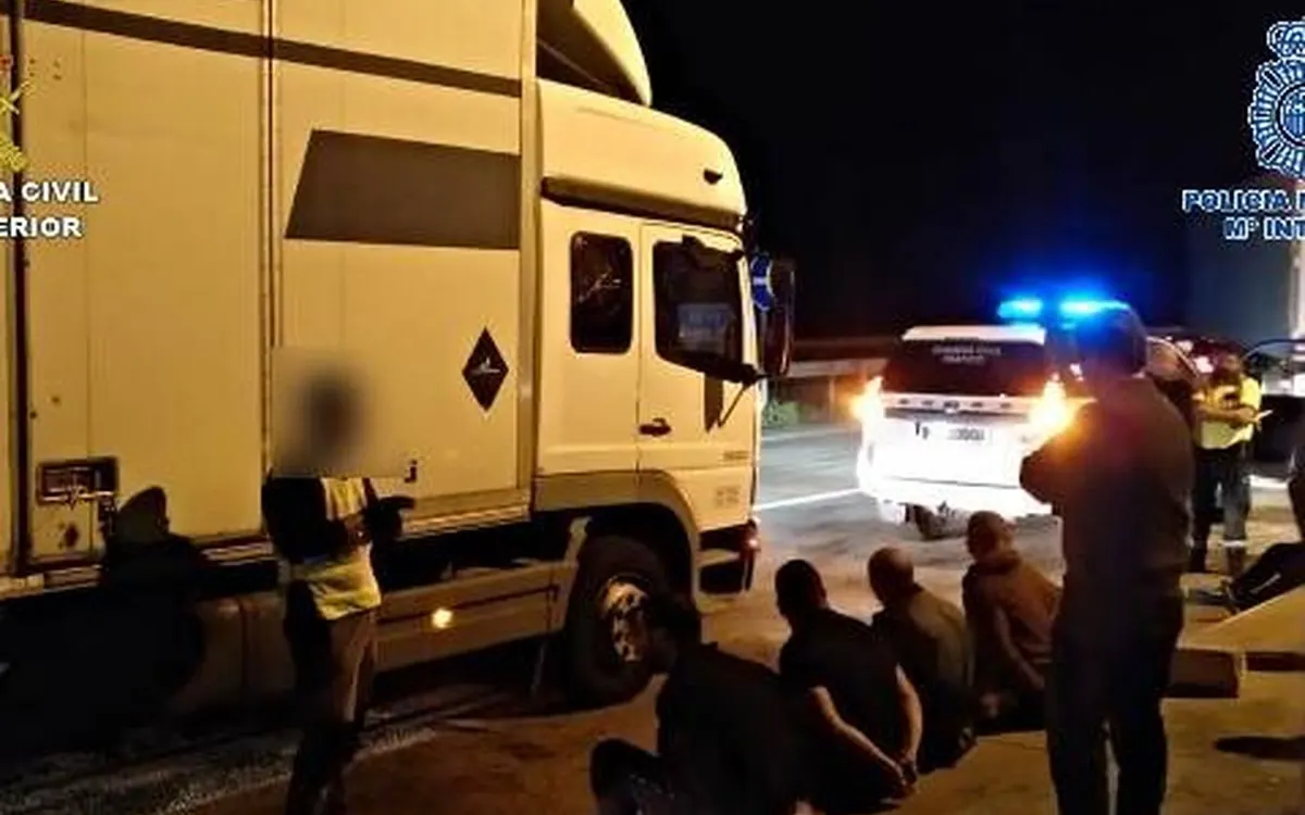 Control nocturno de la Guardia Civil y la Policía Nacional a un camión, con varias personas detenidas sentadas en el arcén